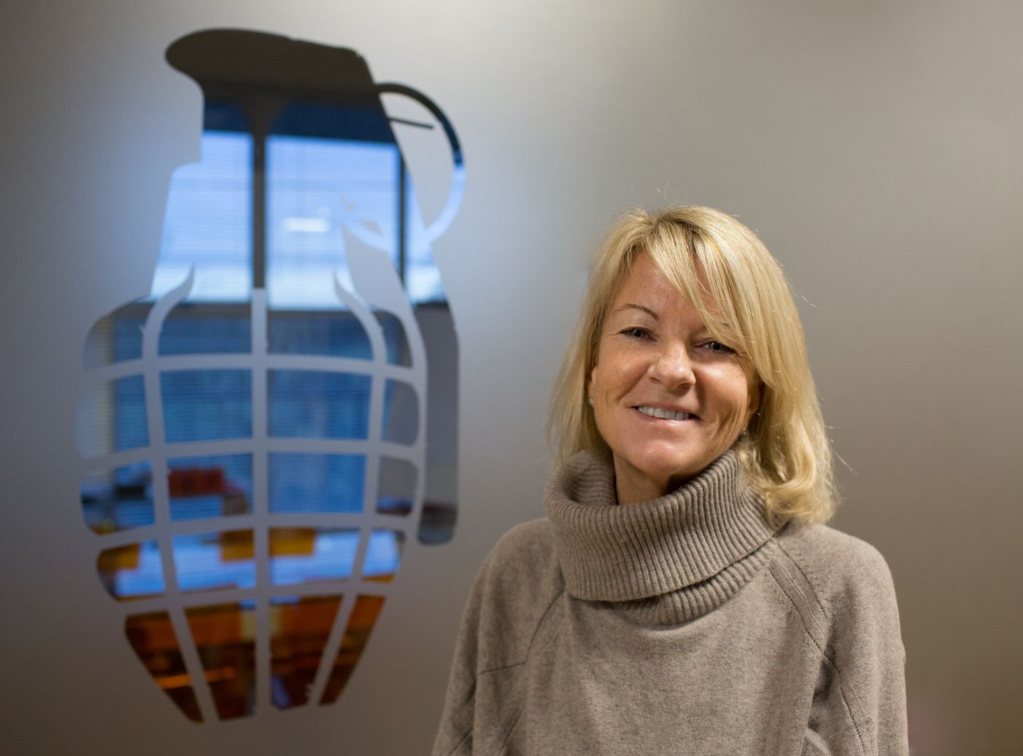 Image of Juliet Barratt, Co-Founder of Grenade stood next to Grenade Logo