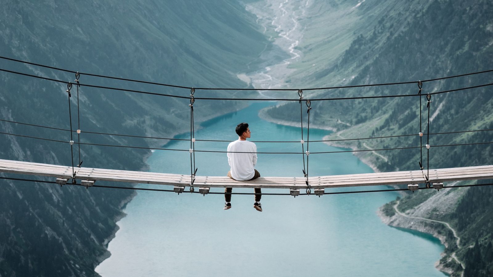 Man sat on a bridge above a river