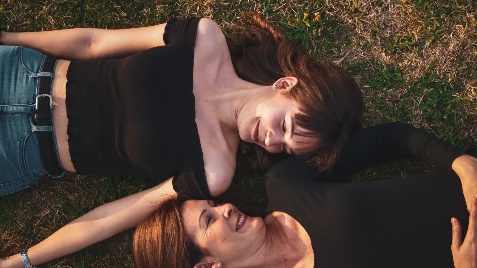 2 women lay on grass smiling and laughing