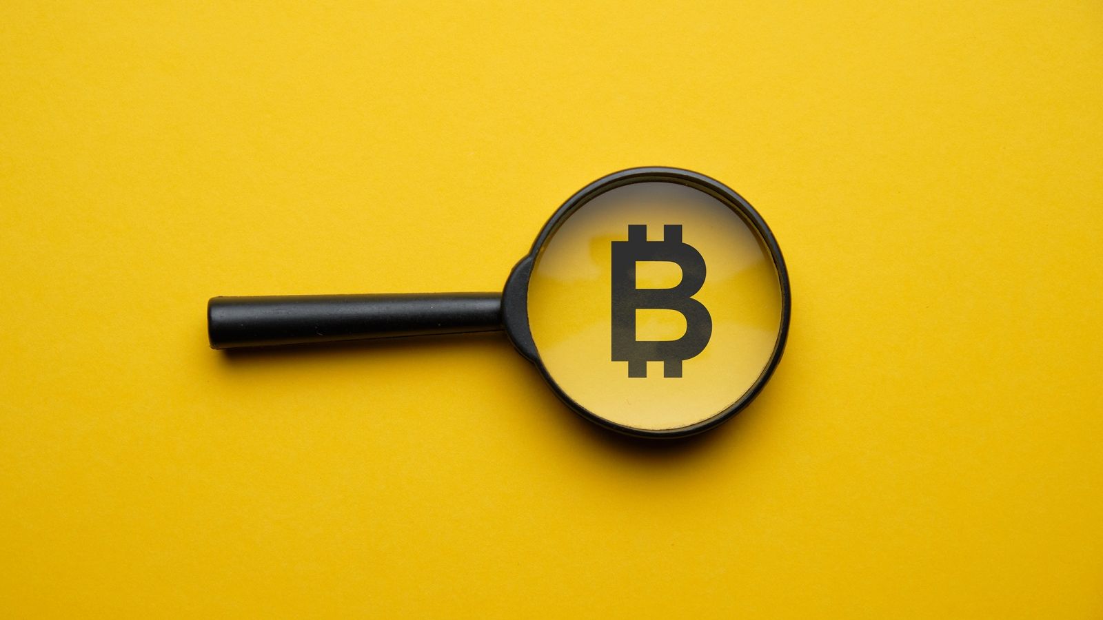Image of a magnifying glass at the bitcoin logo on a yellow background