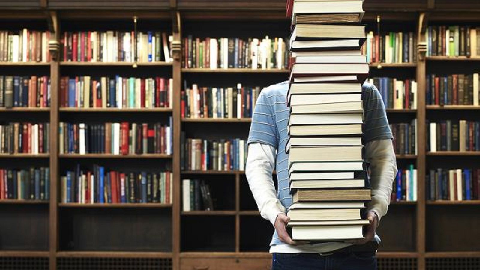Image of a person holding a pile of books